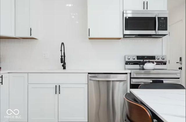 8744 Montery Ct, Indianapolis, IN 46226 - kitchen featuring appliances with stainless steel finishes, white cabinets, a sink, and light stone countertops
