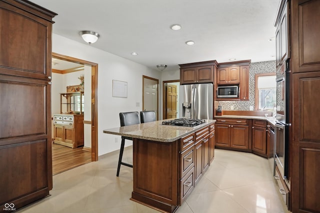 12335 Old Stone Dr, Indianapolis, IN 46236 - kitchen featuring appliances with stainless steel finishes, a kitchen breakfast bar, a kitchen island, light tile patterned floors, and light stone counters