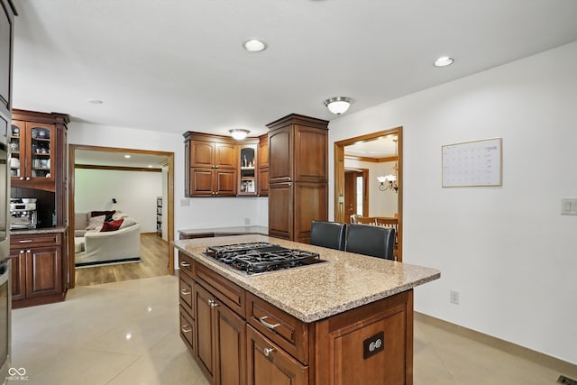12335 Old Stone Dr, Indianapolis, IN 46236 - kitchen featuring stainless steel gas stovetop, a kitchen island, glass insert cabinets, light stone counters, and recessed lighting