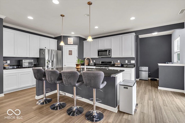 13495 Forest Glade Dr, Fishers, IN 46037 - kitchen with stainless steel appliances, light wood-style floors, a kitchen breakfast bar, ornamental molding, and a center island with sink