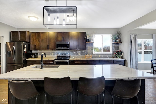 1664 Woodside Cir, Franklin, IN 46131 - kitchen with appliances with stainless steel finishes, backsplash, dark brown cabinetry, pendant lighting, and a center island with sink