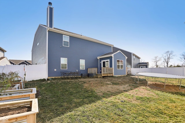 1664 Woodside Cir, Franklin, IN 46131 - rear view of house featuring a trampoline, a chimney, a fenced backyard, and a deck
