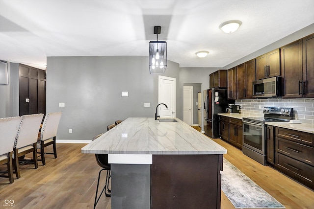 1664 Woodside Cir, Franklin, IN 46131 - kitchen featuring stainless steel appliances, a breakfast bar, decorative backsplash, dark brown cabinetry, and light wood-style flooring