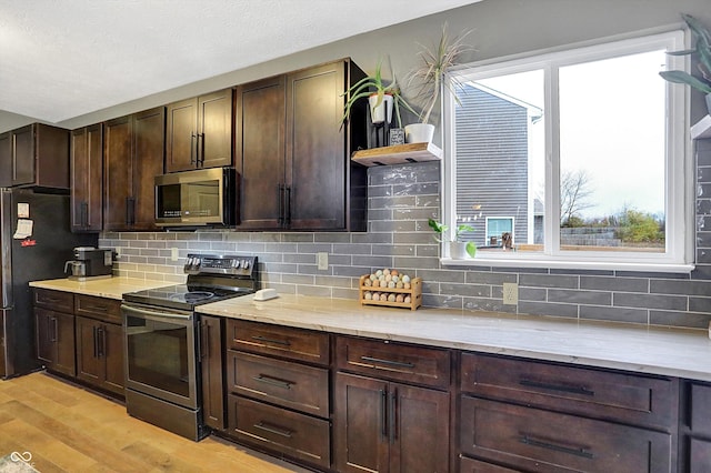 1664 Woodside Cir, Franklin, IN 46131 - kitchen with appliances with stainless steel finishes, light wood-style floors, dark brown cabinets, and tasteful backsplash