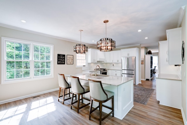 9154 Sargent Manor Ct, Indianapolis, IN 46256 - kitchen featuring stainless steel appliances, a chandelier, white cabinetry, light wood-style floors, and a kitchen island with sink