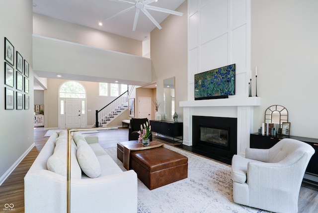 9154 Sargent Manor Ct, Indianapolis, IN 46256 - living room featuring stairs, wood finished floors, a ceiling fan, a large fireplace, and a towering ceiling