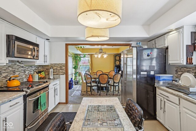 6210 Mckinley Ct, Indianapolis, IN 46220 - kitchen with stainless steel appliances, white cabinetry, light countertops, and decorative backsplash