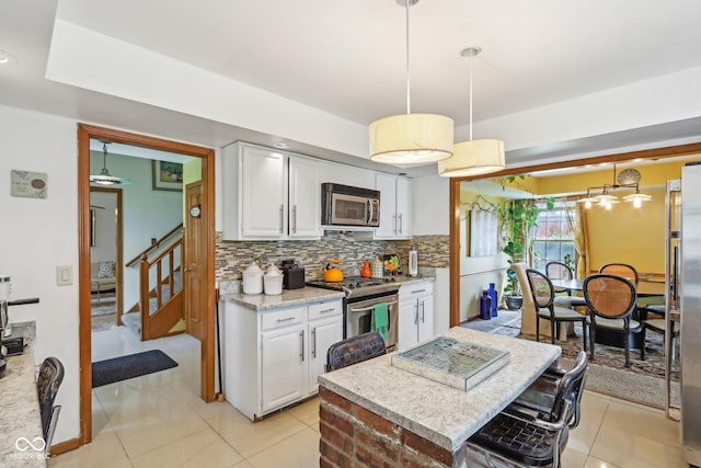 6210 Mckinley Ct, Indianapolis, IN 46220 - kitchen featuring stainless steel appliances, decorative backsplash, white cabinetry, and pendant lighting