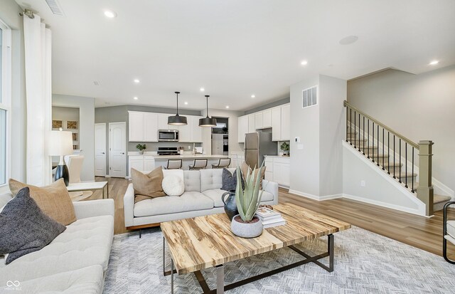 7145 Firestone Rd, Whitestown, IN 46075 - living area featuring light wood-style flooring, stairs, recessed lighting, and baseboards