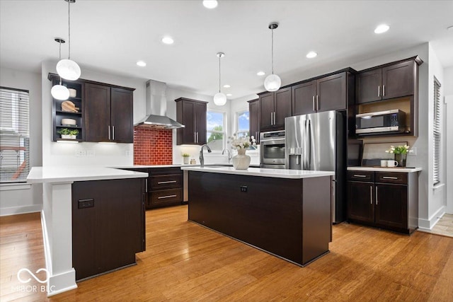 2448 Broadway St, Indianapolis, IN 46205 - kitchen featuring wall chimney exhaust hood, appliances with stainless steel finishes, dark brown cabinets, light countertops, and a center island