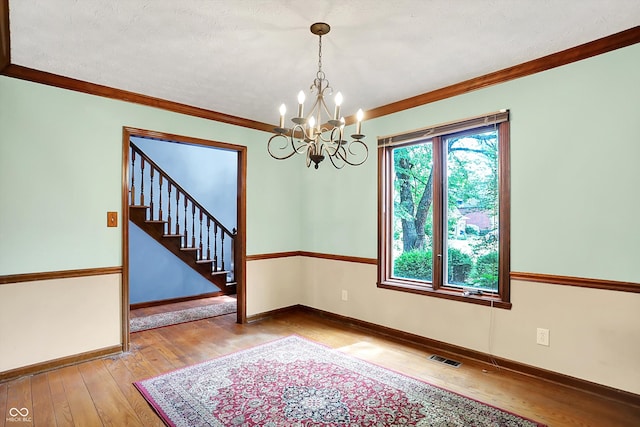 50 Charing Cross Rd, Indianapolis, IN 46217 - empty room featuring wood-type flooring, a chandelier, baseboards, crown molding, and stairs