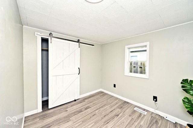 4910 W Caven St, Indianapolis, IN 46241 - unfurnished bedroom featuring wood finished floors, a barn door, ornamental molding, and baseboards