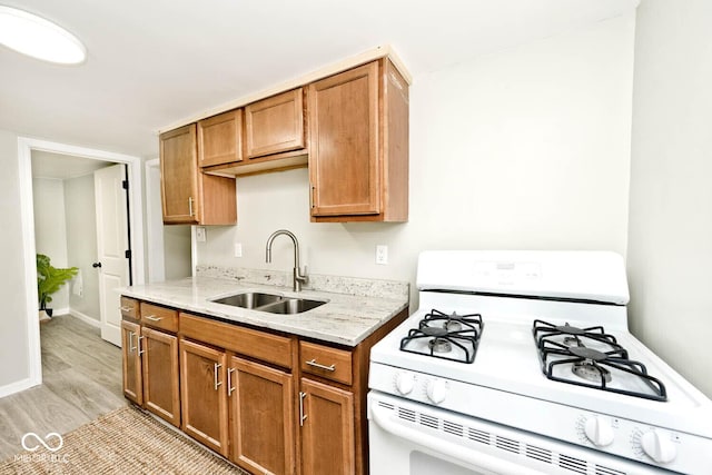 4910 W Caven St, Indianapolis, IN 46241 - kitchen with gas range gas stove, a sink, light wood finished floors, light stone countertops, and brown cabinets