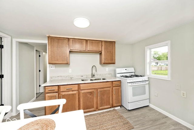 4910 W Caven St, Indianapolis, IN 46241 - kitchen featuring a sink, white gas range, light wood finished floors, light countertops, and baseboards