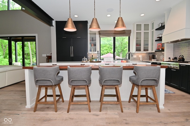 7070 Dean Rd, Indianapolis, IN 46220 - kitchen with custom range hood, stainless steel gas cooktop, dark cabinetry, backsplash, and plenty of natural light