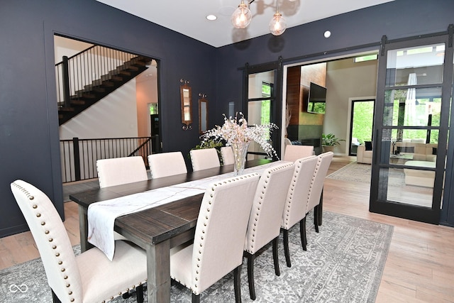 7070 Dean Rd, Indianapolis, IN 46220 - dining space featuring a barn door, light wood-style flooring, stairs, recessed lighting, and a chandelier