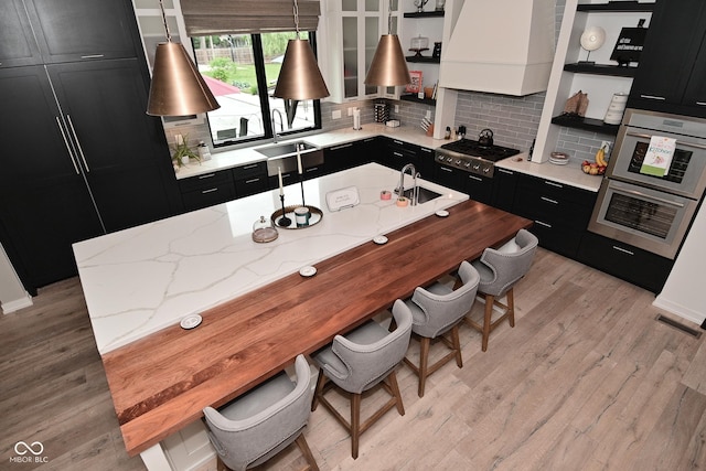 7070 Dean Rd, Indianapolis, IN 46220 - kitchen with dark cabinetry, open shelves, a sink, and light wood-style flooring