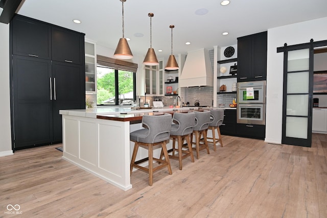 7070 Dean Rd, Indianapolis, IN 46220 - kitchen with open shelves, dark cabinetry, custom exhaust hood, multiple ovens, and a barn door