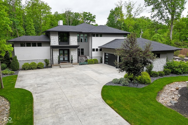 7070 Dean Rd, Indianapolis, IN 46220 - prairie-style house featuring stone siding, french doors, a chimney, a garage, and concrete driveway