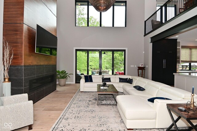 7070 Dean Rd, Indianapolis, IN 46220 - living room featuring a high ceiling, light wood-style floors, healthy amount of natural light, a tiled fireplace, and baseboards