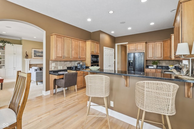 16502 Grand Cypress Dr, Noblesville, IN 46060 - kitchen with black appliances, arched walkways, decorative backsplash, a kitchen breakfast bar, and a peninsula