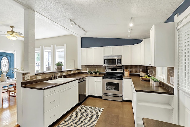 514 Dorman St, Indianapolis, IN 46202 - kitchen with stainless steel appliances, a sink, track lighting, dark countertops, and a textured ceiling