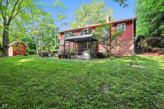 1712 S Flatrock River Rd, Rushville, IN 46173 - back of property featuring a yard, a gazebo, stairway, brick siding, and a chimney