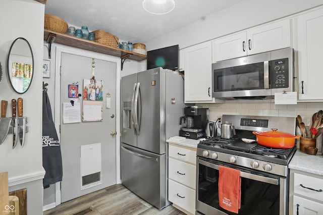 1712 S Flatrock River Rd, Rushville, IN 46173 - kitchen with stainless steel appliances, white cabinetry, tasteful backsplash, light wood-type flooring, and light stone counters