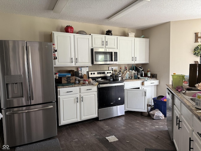 kitchen with appliances with stainless steel finishes, a textured ceiling, white cabinetry, dark wood finished floors, and light stone countertops