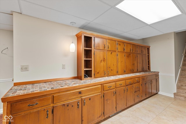 3479 Sugar Loaf Ct, Carmel, IN 46033 - kitchen with open shelves, a drop ceiling, tile countertops, brown cabinetry, and light tile patterned flooring