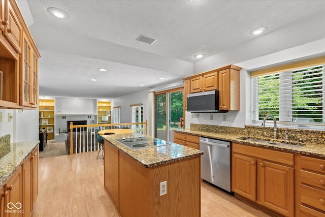3479 Sugar Loaf Ct, Carmel, IN 46033 - kitchen featuring appliances with stainless steel finishes, a center island, a textured ceiling, light wood finished floors, and healthy amount of natural light