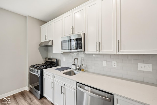 15418 Tattersalls Ln, Fishers, IN 46040 - kitchen featuring stainless steel appliances, light wood-style floors, tasteful backsplash, light countertops, and under cabinet range hood