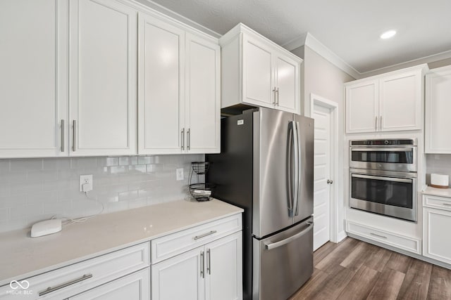 15418 Tattersalls Ln, Fishers, IN 46040 - kitchen with appliances with stainless steel finishes, white cabinets, decorative backsplash, dark wood-style flooring, and crown molding