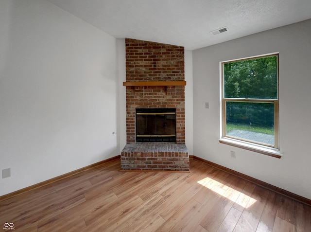 4825 May Ridge Ln, Indianapolis, IN 46254 - unfurnished living room with wood finished floors, baseboards, a brick fireplace, and plenty of natural light