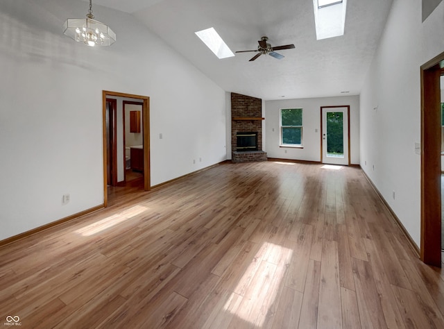 4825 May Ridge Ln, Indianapolis, IN 46254 - unfurnished living room with a skylight, a brick fireplace, light wood-style flooring, high vaulted ceiling, and ceiling fan