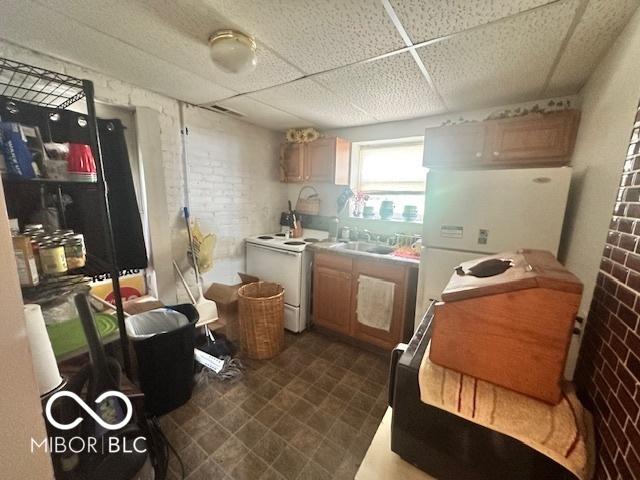 162 N Gladstone Ave, Columbus, IN 47201 - kitchen with a drop ceiling, brick wall, white appliances, a sink, and dark floors