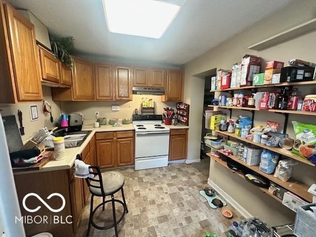 162 N Gladstone Ave, Columbus, IN 47201 - kitchen featuring white electric range, under cabinet range hood, light countertops, a sink, and brown cabinetry