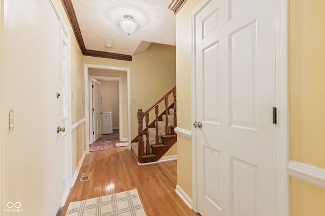 8934 Pinyon Ct, Indianapolis, IN 46260 - hall featuring light wood-type flooring, stairs, a textured ceiling, baseboards, and washer / dryer
