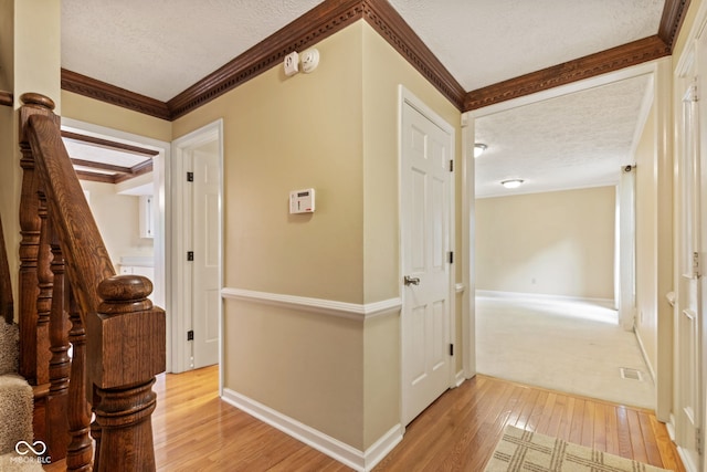 8934 Pinyon Ct, Indianapolis, IN 46260 - corridor featuring a textured ceiling, light wood finished floors, stairway, crown molding, and baseboards