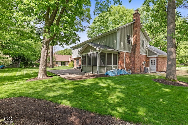 8934 Pinyon Ct, Indianapolis, IN 46260 - rear view of house with a sunroom, brick siding, a chimney, a lawn, and a patio area