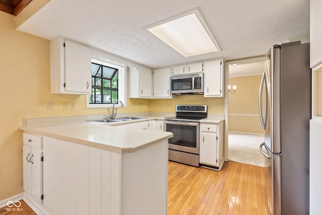8934 Pinyon Ct, Indianapolis, IN 46260 - kitchen with appliances with stainless steel finishes, a sink, a peninsula, a textured ceiling, and white cabinets