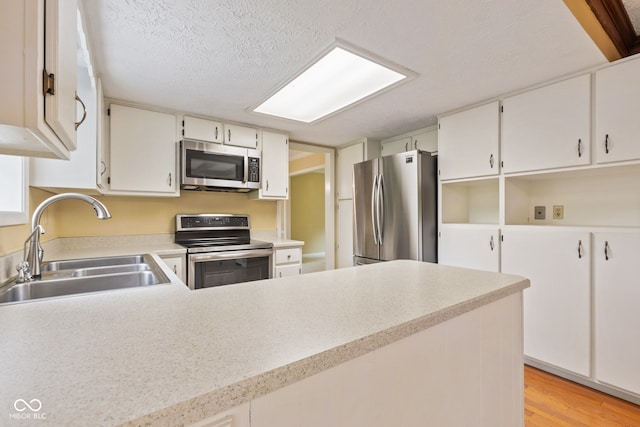 8934 Pinyon Ct, Indianapolis, IN 46260 - kitchen with appliances with stainless steel finishes, a sink, light countertops, light wood-style floors, and a textured ceiling