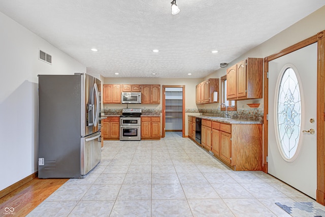 7333 State Road 42, Martinsville, IN 46151 - kitchen with appliances with stainless steel finishes, a sink, recessed lighting, brown cabinetry, and a textured ceiling