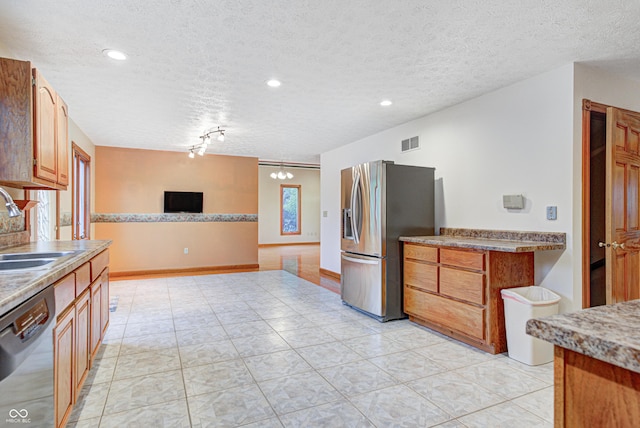 7333 State Road 42, Martinsville, IN 46151 - kitchen featuring appliances with stainless steel finishes, a sink, a textured ceiling, brown cabinetry, and open floor plan