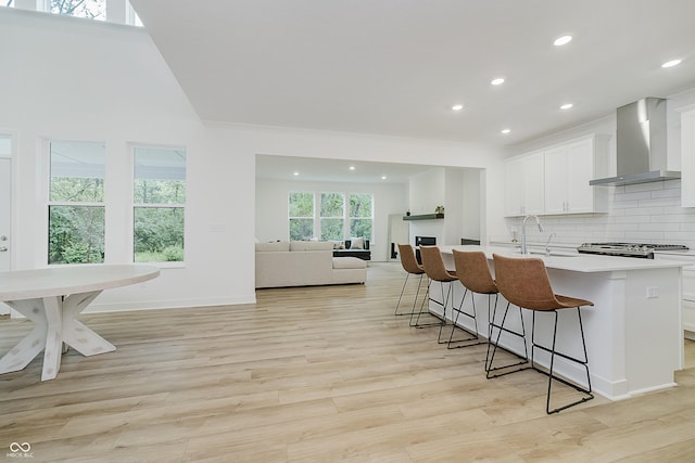 1510 Stonehaven Dr, Westfield, IN 46074 - kitchen with wall chimney range hood, a breakfast bar, a sink, recessed lighting, and white cabinetry
