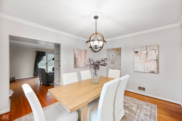 6020 Gladden Dr, Indianapolis, IN 46220 - dining area featuring a chandelier, crown molding, wood finished floors, and baseboards
