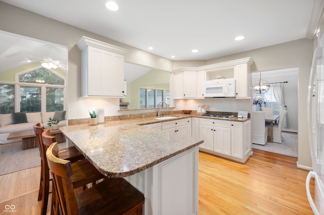 6020 Gladden Dr, Indianapolis, IN 46220 - kitchen with white microwave, a sink, a breakfast bar area, white cabinetry, and gas stovetop