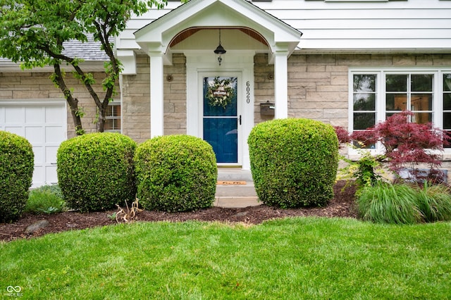 6020 Gladden Dr, Indianapolis, IN 46220 - doorway to property featuring a yard, an attached garage, and stone siding