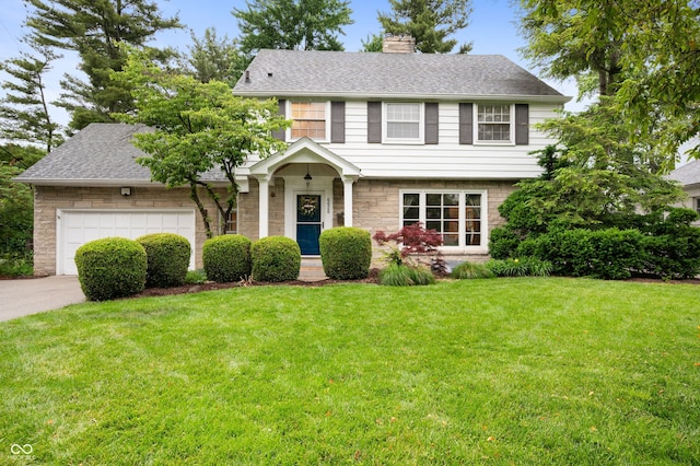 6020 Gladden Dr, Indianapolis, IN 46220 - colonial house featuring a chimney, concrete driveway, a front yard, an attached garage, and a shingled roof