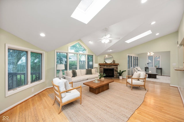 6020 Gladden Dr, Indianapolis, IN 46220 - living room with a skylight, vaulted ceiling, a stone fireplace, and light wood-style floors